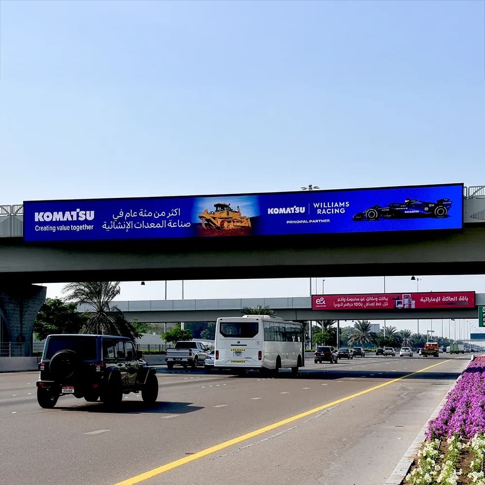 Komatsu bridge banner advertising on Sheikh Zayed Road, Dubai — large-format overpass billboard featuring Komatsu construction equipment and Williams Racing partnership branding, high-impact highway outdoor advertising.